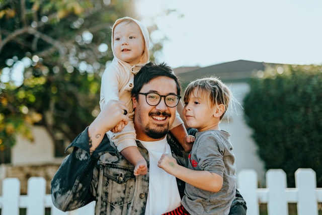 Father carrying his two children, one on this shoulders and the other in his arms